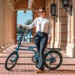 A woman standing next to a bike on a sidewalk