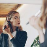 Young woman applying makeup in mirror
